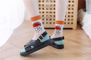 Detailed view of sheer watermelon patterned socks with orange ribbed cuffs and fruit print