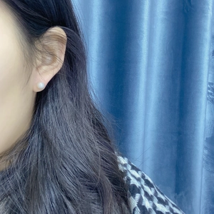 Close-up of a minimalist white freshwater pearl stud earring worn on the ear