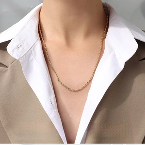 Detailed view of 2mm gold twisted rope chain worn by a model with a brown blazer