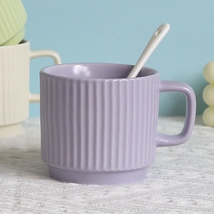 Detail of purple striped ceramic mug with white spoon on lace tablecloth setup