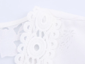 Detail of white dress showing intricate lace embroidery and sheer mesh floral textures