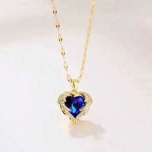 Nahaufnahme der Goldkette mit blauem Herz-Kristall und kleinen Diamanten auf der O-Kette
