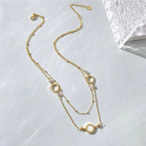 Close-up of double-layer gold necklace with white shell inlay and Roman numerals