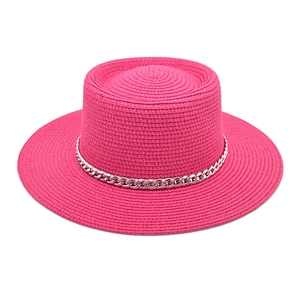 Detail of bright pink straw hat with silver chain decoration and flat top weave