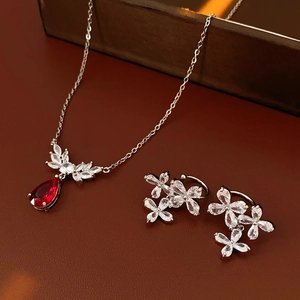 Detail of silver flower necklace and earrings set with red teardrop gemstone