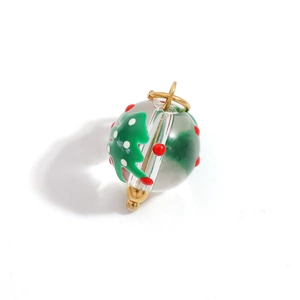 Macro view of Christmas tree and polka dot glass sphere pendant with gold metal hoops