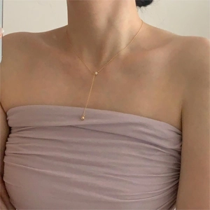 Detail of gold Y-shaped necklace on model showing delicate chain and pendant drop