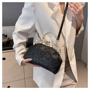 Detailed view of the black shell bag with floral embossing and gold metal handle