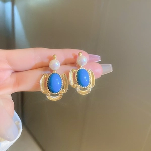 Close-up of vintage gold earrings featuring royal blue stones and white pearls