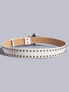 Detail of white punk belt with gold studs and a black star-shaped buckle on gray backdrop