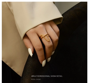 Detail of 18K gold-plated double-layer ring with thin metal chain on index finger