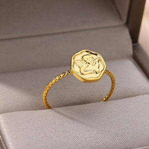 Macro view of a gold-plated stainless steel ring with an angel relief and spiral band