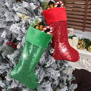 Glittery red and green Christmas stockings with velvet cuffs on a festive fireplace mantel