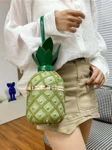 Creative green pineapple handbag with gold studs and leaf handle held by a model