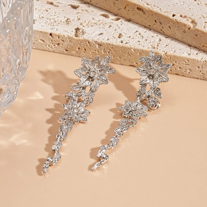 Détails de boucles d'oreilles pendantes fleurs argentées avec motifs floraux et feuilles