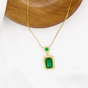 Close-up of emerald green pendant necklace with zircon halo on a wooden tray