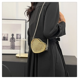 Detail of a heart-shaped gold evening bag with rhinestones and metal chain strap