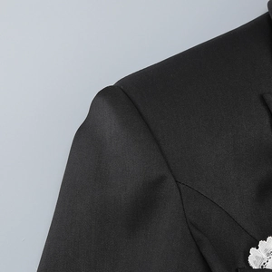 Macro detail of black blazer shoulder showing high-quality twill fabric and refined stitching