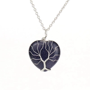 Macro shot of silver wire-wrapped Tree of Life on heart-shaped blue sand stone pendant