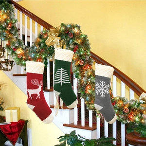 Three knitted Christmas stockings with reindeer, tree and snowflake patterns on a staircase