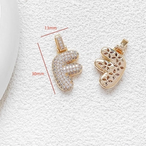Macro detail of letter F pendant with zircons and 30x13mm size specifications