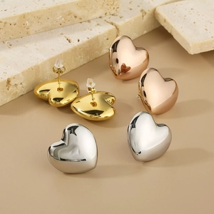 Detailed view of heart stud earrings in gold, silver, and rose gold on natural stone