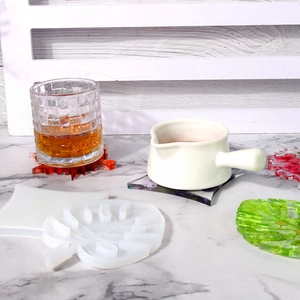 Detail of monstera leaf silicone resin mold with finished colorful leaf-shaped coasters