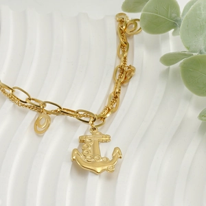Close-up of 18k gold-plated anchor pendant with double chain design on a white surface