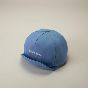 Detail of blue cotton baby baseball cap featuring Bonita Baby embroidery and a smiley face