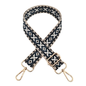 Macro detail of geometric jacquard bag strap with golden metal swivel hooks and adjuster