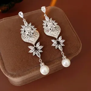 Luxurious silver pearl drop earrings with leaf design and sparkling crystals on brown velvet