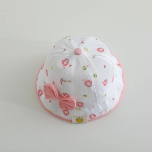 Gros plan d'un chapeau cloche blanc pour bébé avec imprimé donuts et un nœud décoratif rose