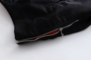 Detaillierte Nahaufnahme einer schwarzen Bomberjacke mit orangefarbenem Innenfutter