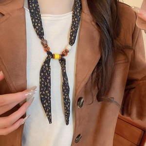 Detailed close-up of ethnic beaded necklace with golden fabric and resin accents on a model