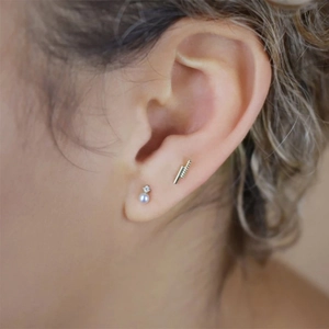 Macro detail of S925 silver pearl earring set with zirconia on a female model's ear