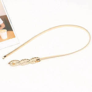 Detail of golden spring waist belt with leaf-shaped metal buckle on white background