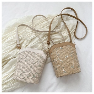 Gros plan du sac seau tressé avec broderie florale délicate et bandoulière en cuir