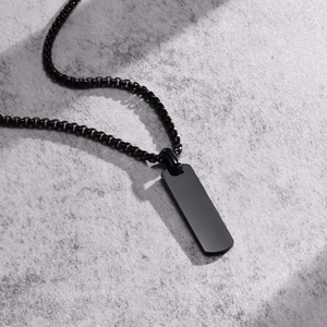 Detailed macro view of matte black stainless steel rectangular pendant on a ball chain