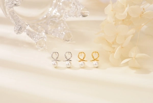 Detail of twisted metal stud earrings with pearls in gold and silver finish