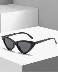 Detail of glossy black triangle cat-eye sunglasses on a white geometric display