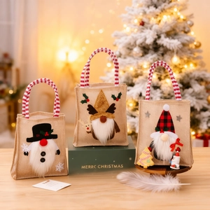 Three burlap Christmas gift bags with gnome and snowman motifs on a festive wood background