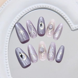 Faux ongles œil de chat violets avec motifs lune et étoiles sur un plateau blanc