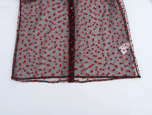 Detail of sheer black mesh fabric with red flocked hearts and black button closure