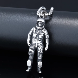 Macro shot of a vintage silver astronaut pendant necklace with intricate suit textures