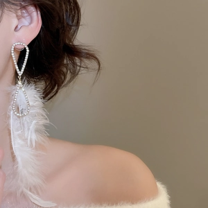 Nahaufnahme eleganter Feder-Ohrringe mit glitzernden Strasssteinen und Goldbeschichtung