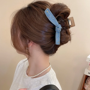 Detailed view of denim bow hair claw clip with colorful rhinestones on female hair