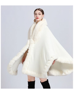 Detail of white knit poncho featuring a soft faux rabbit fur collar and elegant trim