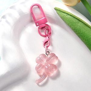 Rosa Kleeblatt-Schlüsselanhänger aus Harz mit Glitzer und Karabiner auf weißem Tablett