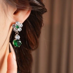 Close-up of a luxury silver floral earring with emerald green and clear zircon stones