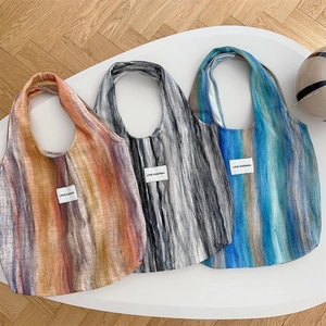 Détail de trois grands sacs cabas en maille rayée avec des étiquettes LOVE SOZAKKA